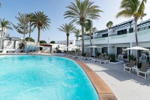 una piscina con palmeras y un edificio en Apartment at 50m from the ocean, with Wifi and pool, in Puerto del Carmen en Puerto del Carmen