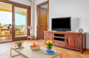 a living room with a television on a wooden entertainment center at Appartamento Le Palme Costa Smeralda in Arzachena