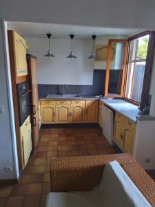 a large kitchen with yellow cabinets and a sink at MAISON DE VILLAGE ST MARCELLIN in Veynes