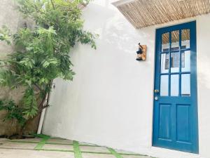 niebieskie drzwi na białym budynku z drzewem w obiekcie Balai Lawaan Charming Sanctuary w mieście Iloilo