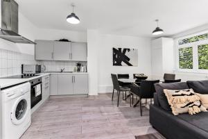 uma cozinha e sala de estar com um sofá e uma mesa em Finsbury Park Station Apartment! (B) em Londres