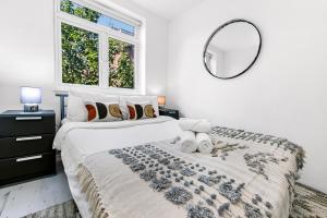 a white bedroom with a large bed with a mirror at Finsbury Park Station Apartment! (B) in London