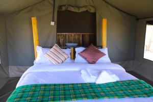 ein Schlafzimmer mit einem großen Bett in einem Zelt in der Unterkunft Emunyan Mara Camp in Narok