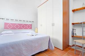 1 dormitorio con 1 cama grande y cabecero rosa en Appartamento Le Palme Costa Smeralda, en Arzachena