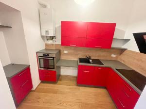 una pequeña cocina con armarios rojos y fregadero en 75 m2 Stylish Apartment with Free Parking, en Viena