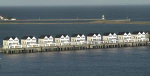 eine Reihe weißer Häuser auf einer Anlegestelle im Wasser in der Unterkunft Ferienwohnung OstseeBrise in Olpenitz