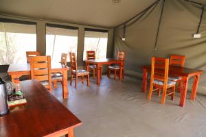 ein Esszimmer mit Tischen und Stühlen in einem Zelt in der Unterkunft Emunyan Mara Camp in Narok