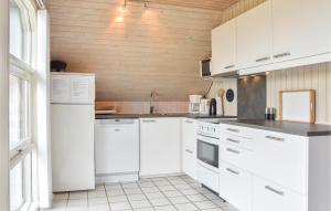 Nørre LyngvigにあるStunning Home In Ringkbing With Kitchenの白い家電製品と木製の壁が備わるキッチン