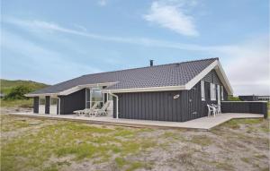 ヴィデ・サンデにあるHoliday Home Hvide Sande With A Fireplace 3の黒い家 椅子2脚付きのデッキ