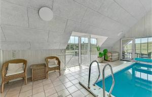 a swimming pool with chairs and a table and a swimming pool at Nice Home In Ringkbing With Sauna in Klegod