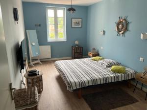 Les chambres du Golf في Espalais: غرفة نوم زرقاء مع سرير وتلفزيون