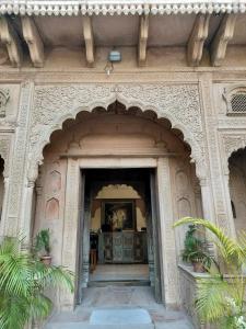 une entrée dans un bâtiment avec une arche et des plantes dans l'établissement Rigmor haveli, à Jodhpur
