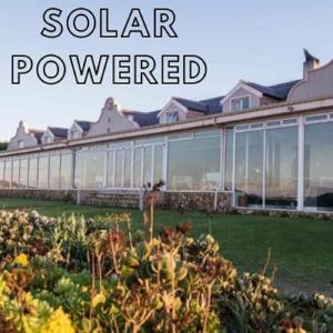 a garden in front of a building with the words solar powered at Blue Bay Lodge in Saldanha