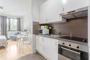 a kitchen with white cabinets and a table with a microwave at Chill Apartments Studio in Warsaw