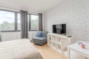 ワルシャワにあるChill Apartments Studioのベッドルーム(ベッド1台、テレビ、椅子付)