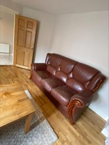 a brown leather couch in a living room with a table at Cosy 4 Bedroom Galway House with Rear Garden Patio in Galway