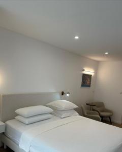 een slaapkamer met een wit bed en een stoel bij Le cap dagde in Cap d'Agde