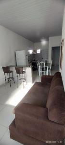 a living room with a brown couch and a kitchen at casa temporada em Barreirinhas in Marinheiros