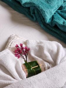 a green engagement ring and a pink flower in a towel at Pousada Vila Gaia in Santo André