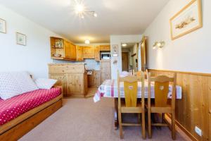a bedroom with a table and a bed and a kitchen at le plein soleil méribel mottaret in Les Allues
