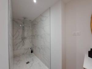 y baño con ducha y azulejos de mármol blanco. en Mascate - Appartement Climatisé en Hypercentre, en Reims