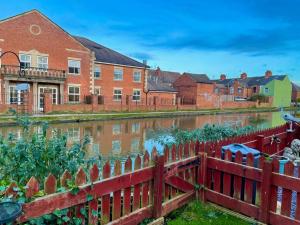 una valla roja frente a una casa y un río en Silver Stag Properties, Cozy 2 BR Home w Parking en Loughborough
