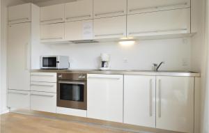ThorsmindeにあるBeautiful Home In Ulfborg With 2 Bedrooms, Sauna And Wifiの白いキャビネット、シンク、電子レンジ付きのキッチンが備わります。