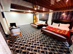 a bedroom with two beds and a table and a bed sqor at Hotel Crown Pine Pahalgam in Anantnāg