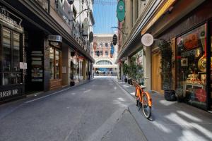 an orange bike parked on a street between buildings at 'Eclectic on Degraves St' A High-End Heritage Abode in Melbourne