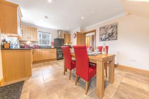 a kitchen with a wooden table and red chairs at Springbank Cottage, luxury Lake District cottage in Coniston in Coniston