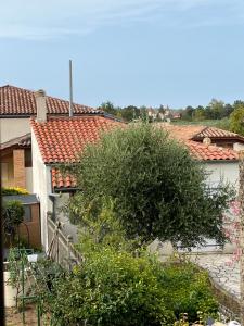 a tree in front of a white building with red roofs at Les chambres du Golf in Espalais