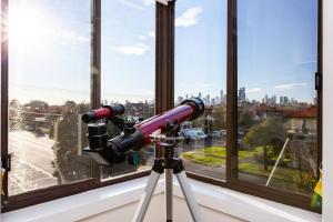 a telescope on a tripod in front of a window at 'The Lighthouse' Character-filled Abode near Beach in Melbourne