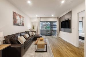 a living room with a brown leather couch and a tv at Spacious Inner-city Stay with King Bed and Balcony in Melbourne