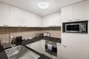 a kitchen with white cabinets and a microwave at Spacious Inner-city Stay with King Bed and Balcony in Melbourne