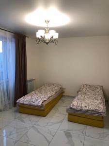 two beds in a room with a chandelier at LUXflats Rivne in Rivne