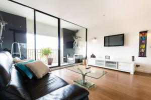Una sala de estar con un sofá de cuero y un televisor. en Southside St Kilda Seclusion with Balcony and Parking, en Melbourne