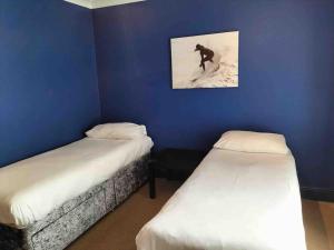 a room with two beds and a man riding a snowboard at Central Newquay Terrace House in Newquay