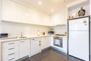 a white kitchen with white cabinets and a refrigerator at Southbank Splendour - A Sky High Stay with Parking in Melbourne