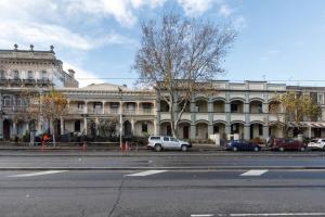 duży biały budynek z samochodami zaparkowanymi przed nim w obiekcie Nicholson's Nest - A Balcony Studio in Funky Fitzroy w Melbourne