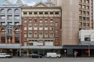 een groot bakstenen gebouw met auto's geparkeerd voor het bij Studio Elizabeth - A Cosy and Central CBD Hidden Gem in Melbourne
