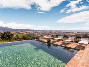 einen Infinity-Pool mit Stühlen und Bergen im Hintergrund in der Unterkunft Comfortable apartment with stunning views near hot springs in Celle sul Rigo