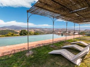 un par de sillones bajo una sombrilla de paja junto a un cuerpo de agua en Comfortable apartment with stunning views near hot springs en Celle sul Rigo