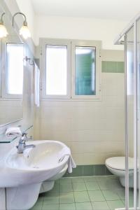 a white bathroom with a sink and a toilet at La Cecinella Apartments in Marina di Cecina