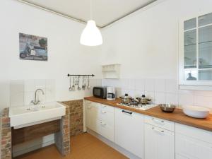 a kitchen with white cabinets and a sink and a stove at Traditional Apartment in Poffabro with Fireplace in Frisanco