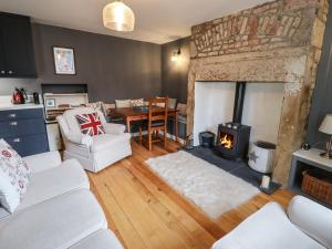 a living room with a fireplace and a table at Grebe Cottage in Alnwick