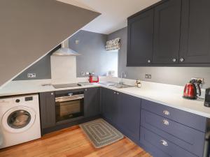 a kitchen with blue cabinets and a washing machine at Grebe Cottage in Alnwick