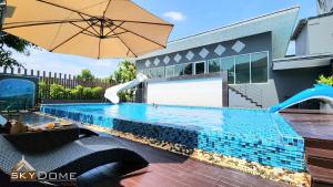 a swimming pool with an umbrella next to a house at Sky dome resotel - โรงแรมสกายโดม รีโซเทล in Bangkok