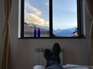 a person laying on a bed looking out of a window at 2br Mountain View Apartment - 250mbps Wifi in Bansko