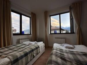 a bedroom with two beds and two windows at 2br Mountain View Apartment - 250mbps Wifi in Bansko