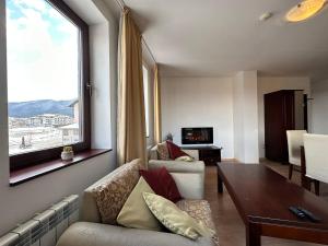 a living room with a couch and a table and a window at 2br Mountain View Apartment - 250mbps Wifi in Bansko